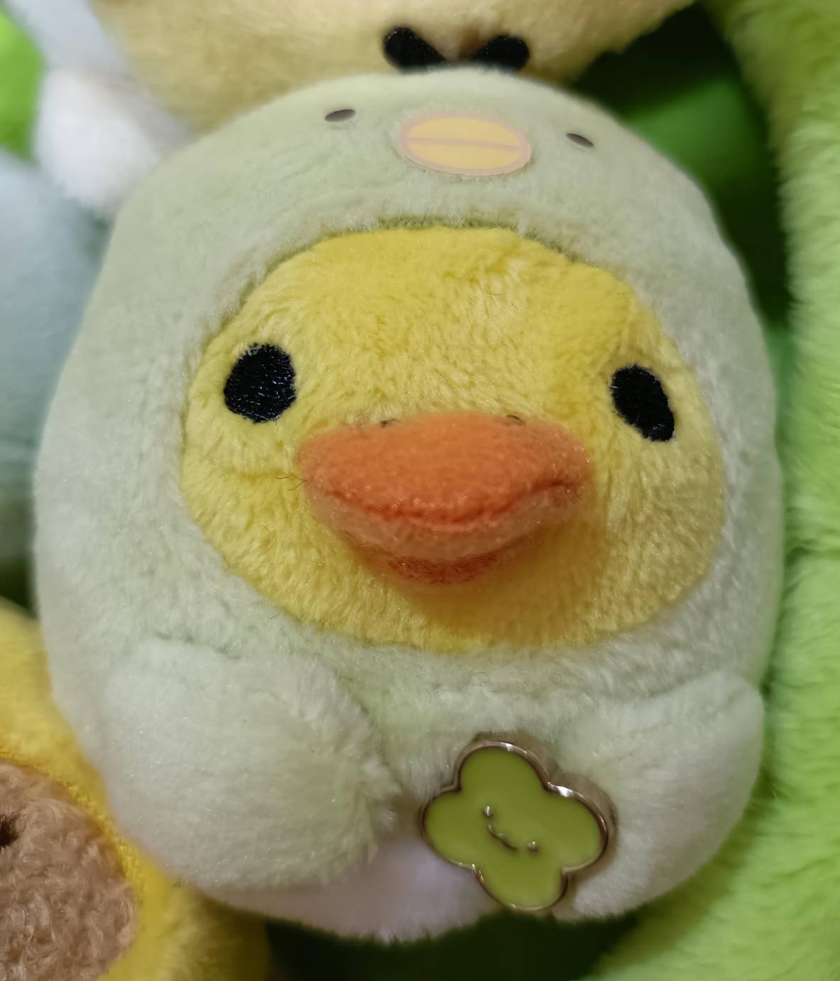 ひよこがすみっコ(淡いミントグリーン)の着ぐるみを着たマスコット。オレンジのくちばしが特徴的、緑のクローバーチャームあり