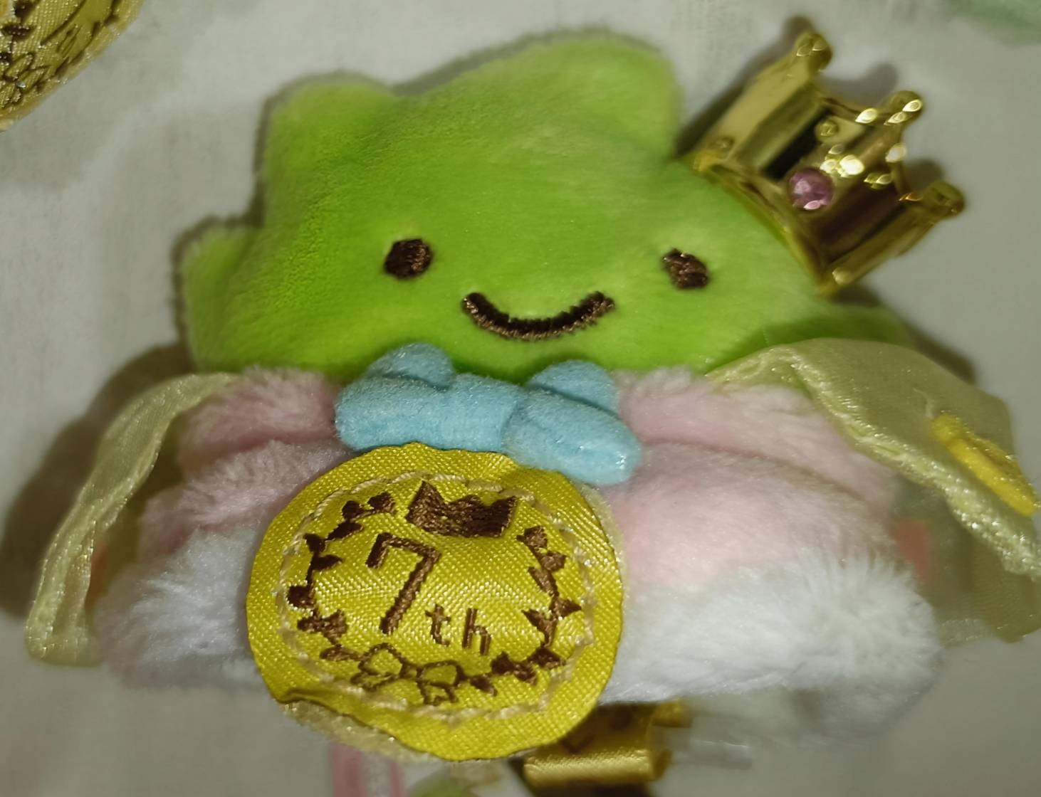 わきやくすみっコ選手権マスコット「とかげ（またはざっそう）」。鮮やかな黄緑ボディ・ピンク石の王冠・水色ボウタイ・7thメダル付き