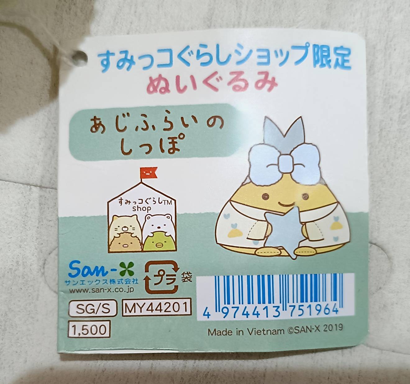 商品タグ拡大。「すみっコぐらしショップ限定ぬいぐるみ」「あじふらいのしっぽ」San-X 2019、品番MY44201、価格1,500円、Made in Vietnam と記載。